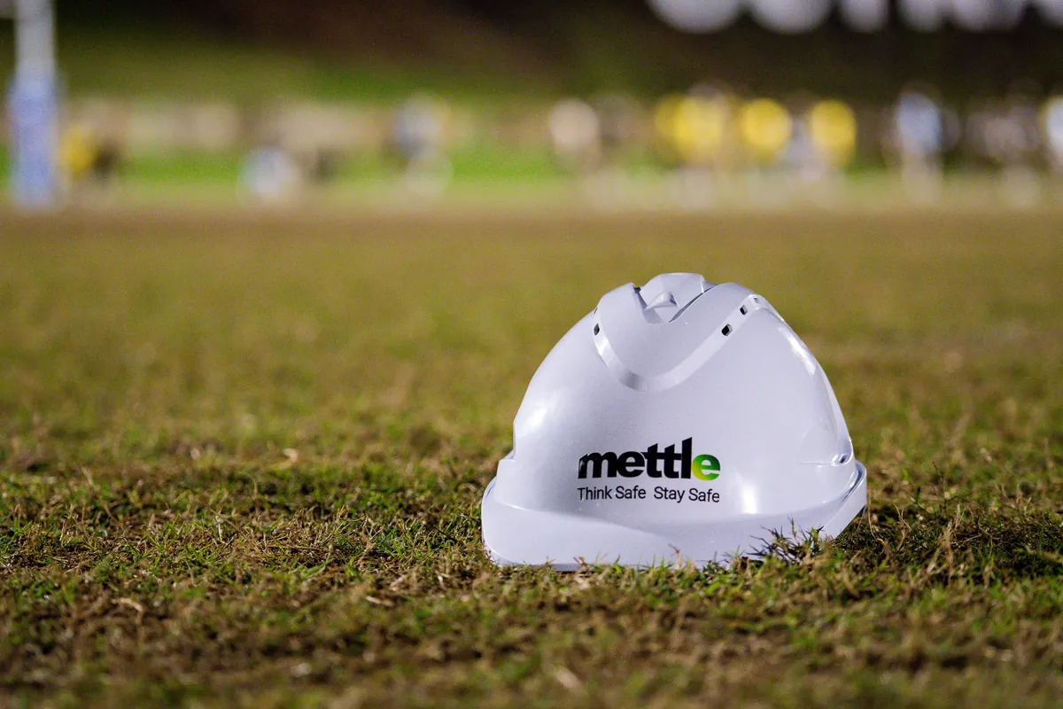White Mettle hard hat printed with Think Safe. Stay Safe resting on the grass